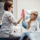 A healthcare worker wearing a mask and gloves gives a high-five to a young girl sitting on a medical chair in a clinic.